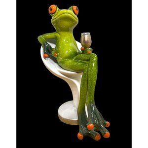 Green Ceramic Frog Figurine With Wine Glass Sitting In Modern White Chair